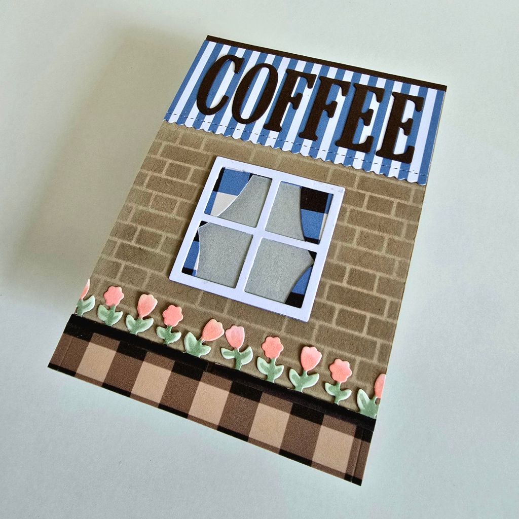 Handmade coffee shop-inspired greeting card with intricate details. The exterior highlights a quaint café design, while the inside surprises with a pop-up couple enjoying their coffee date.